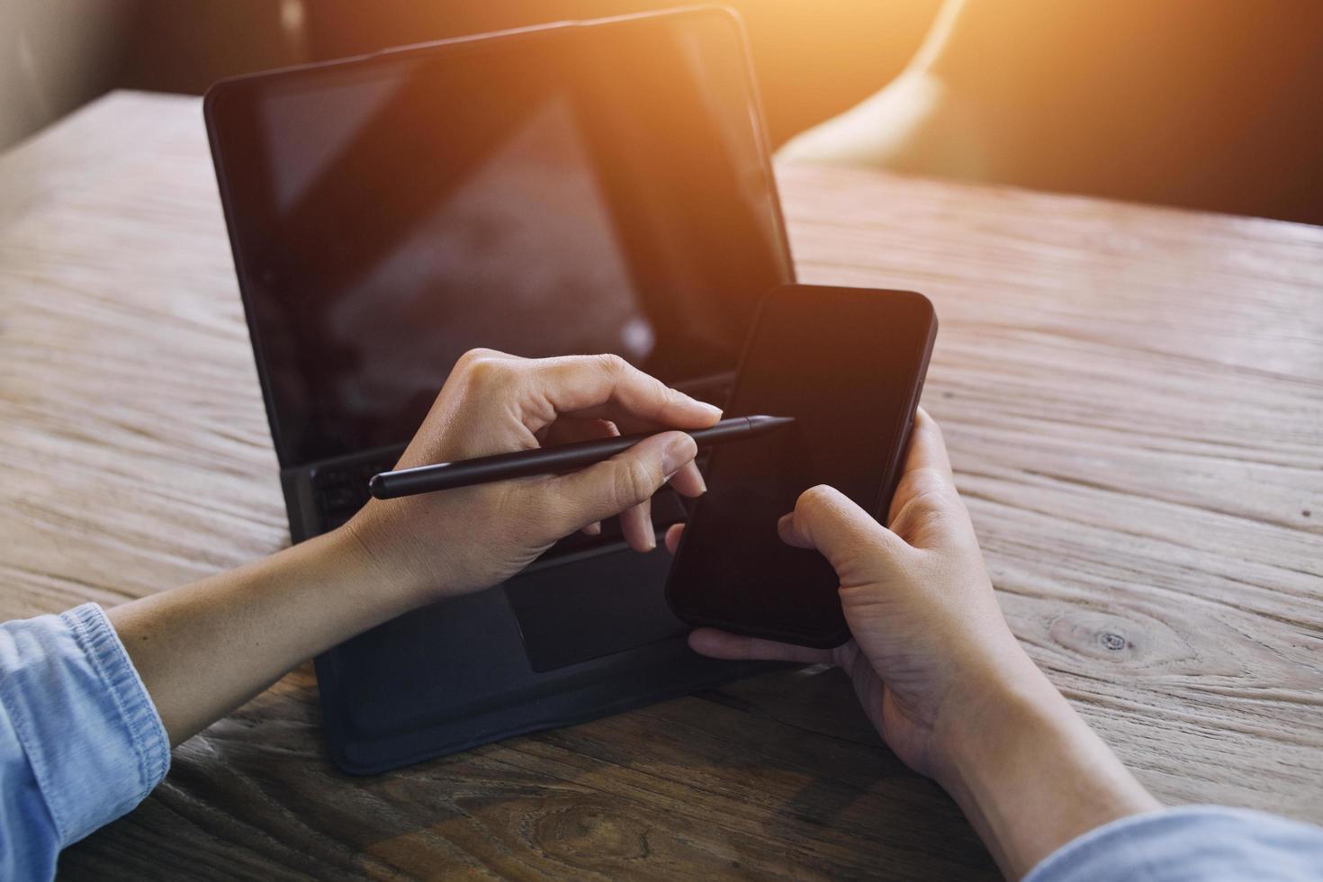 Geschäftsfrau arbeitet mit Laptop-Computer, Tablet und Smartphone im modernen Büro mit virtuellem Symboldiagramm im Modernoffice im Morgenlicht foto