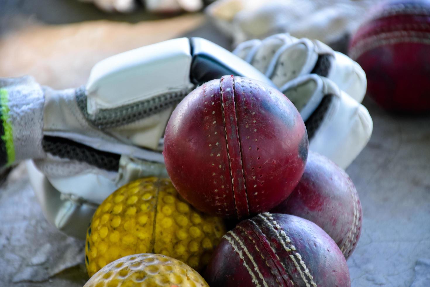 training von cricket-sportgeräten auf dem boden, lederball, handschuhe und schläger, weicher und selektiver fokus auf den ball. foto