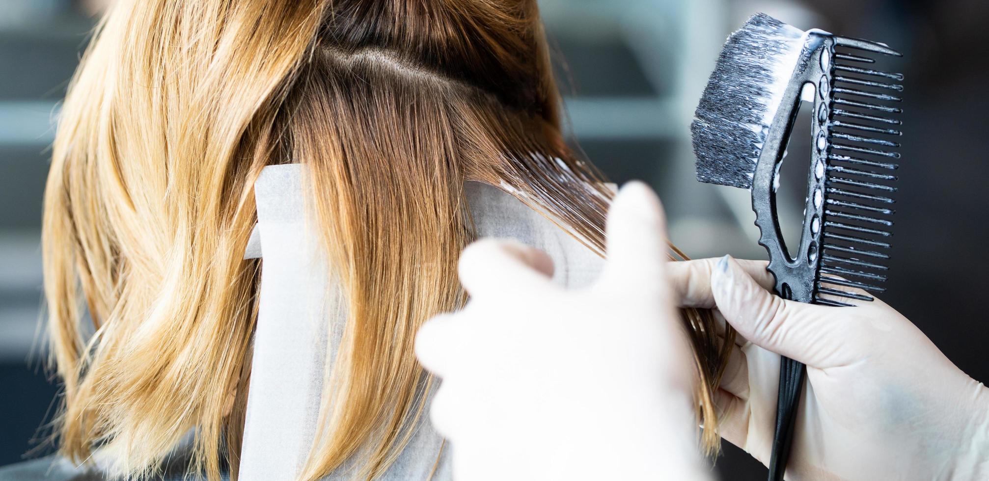 selektiver fokus auf flüssige haarfarbe des haares stilvoll beim frisieren und pflegebehandlung beim stylen von lockigem haar für den kunden. professionelle tätigkeit, schönheits- und modeservice. foto