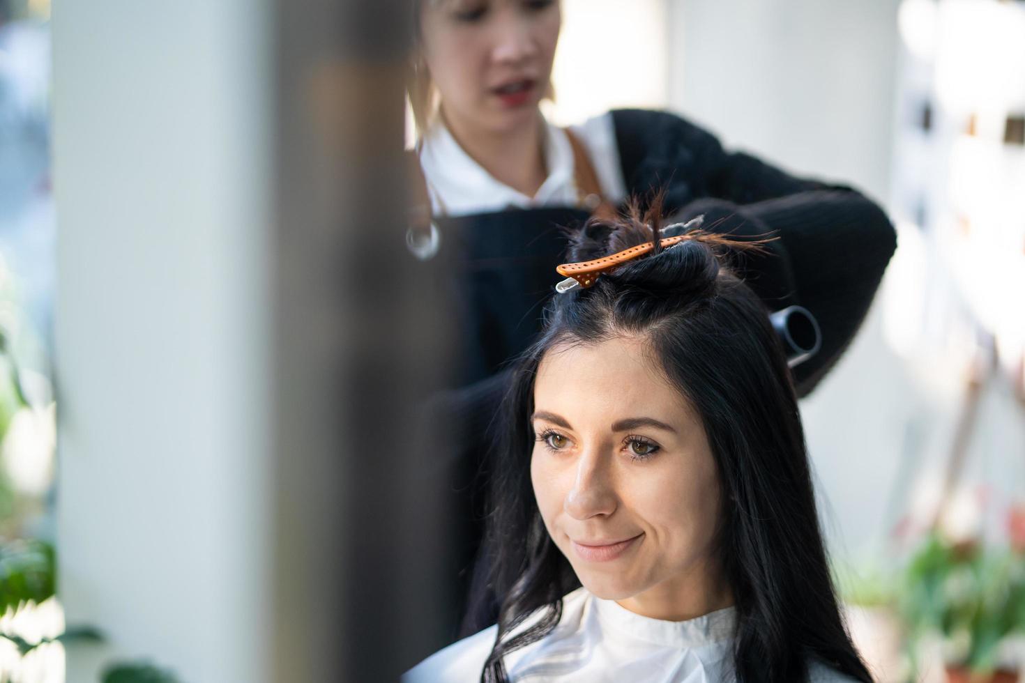 kaukasische frauen mit stilvollem haar, während sie haare schneiden und eine chirurgische gesichtsmaske tragen, während sie haare für den kunden stylen. Berufliche Tätigkeit, Schönheits- und Modeservice neue Normalität foto