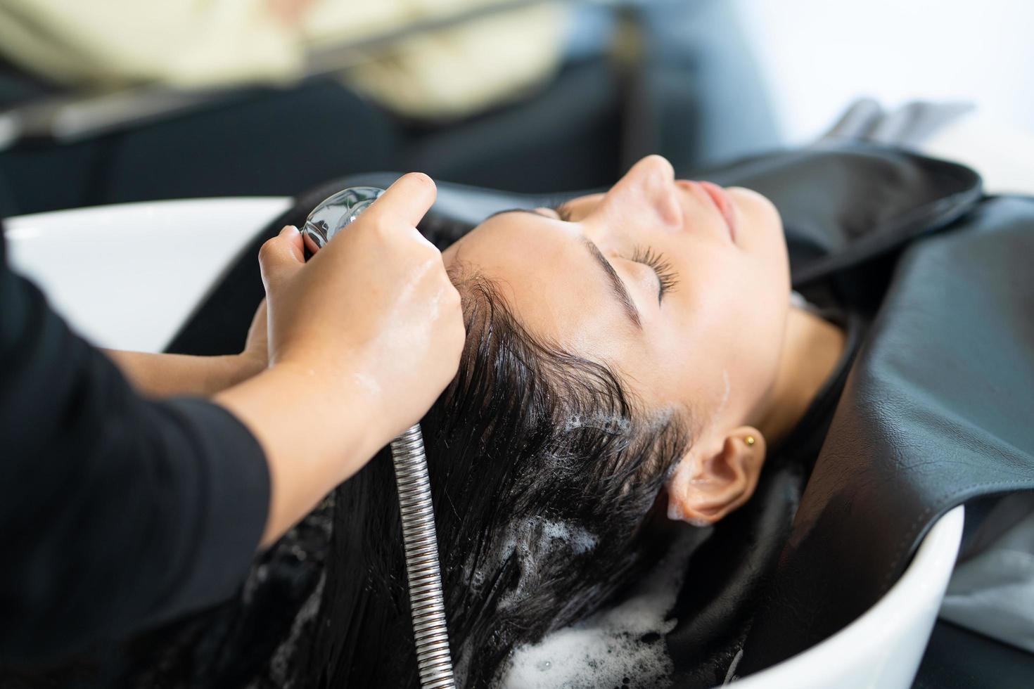 Nahaufnahme von schönen kaukasischen Frauen fühlen sich entspannt und wohl, während sie sich mit Shampoo und Massage die Haare waschen. friseurstudio mit stilvollem haar, schönheits- und modekonzept. foto