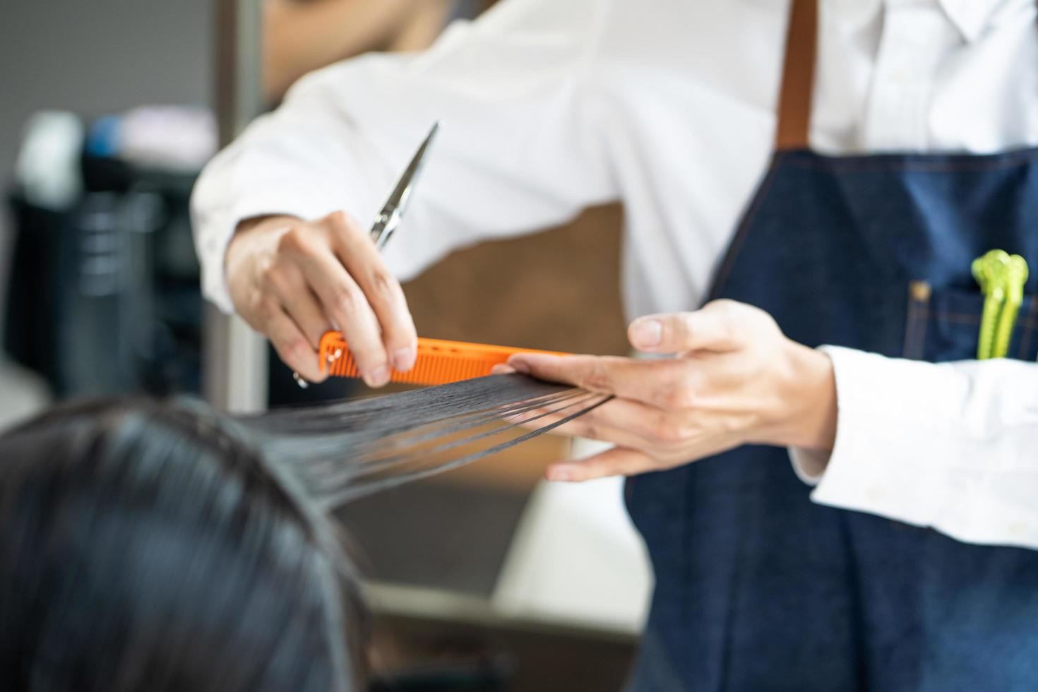 nahaufnahme schuss an der hand des haares stilvoll, während haarschnitt und friseur und behandlung beim stylen der haare für den kunden. Beruf, Schönheits- und Modedienstleistungsberuf. foto