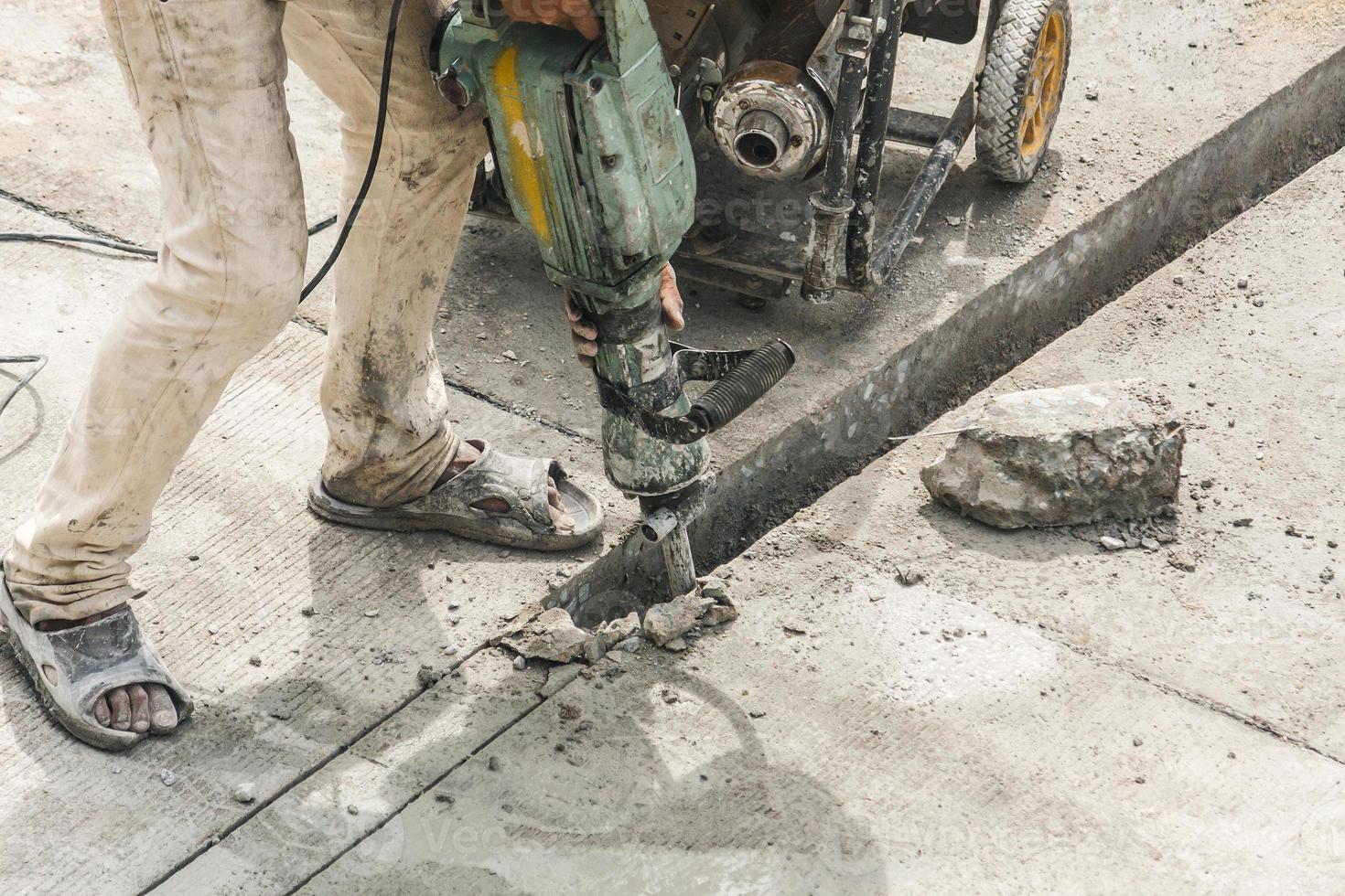 bauarbeiter, der bohrhammer verwendet, der betonoberfläche bohrt foto