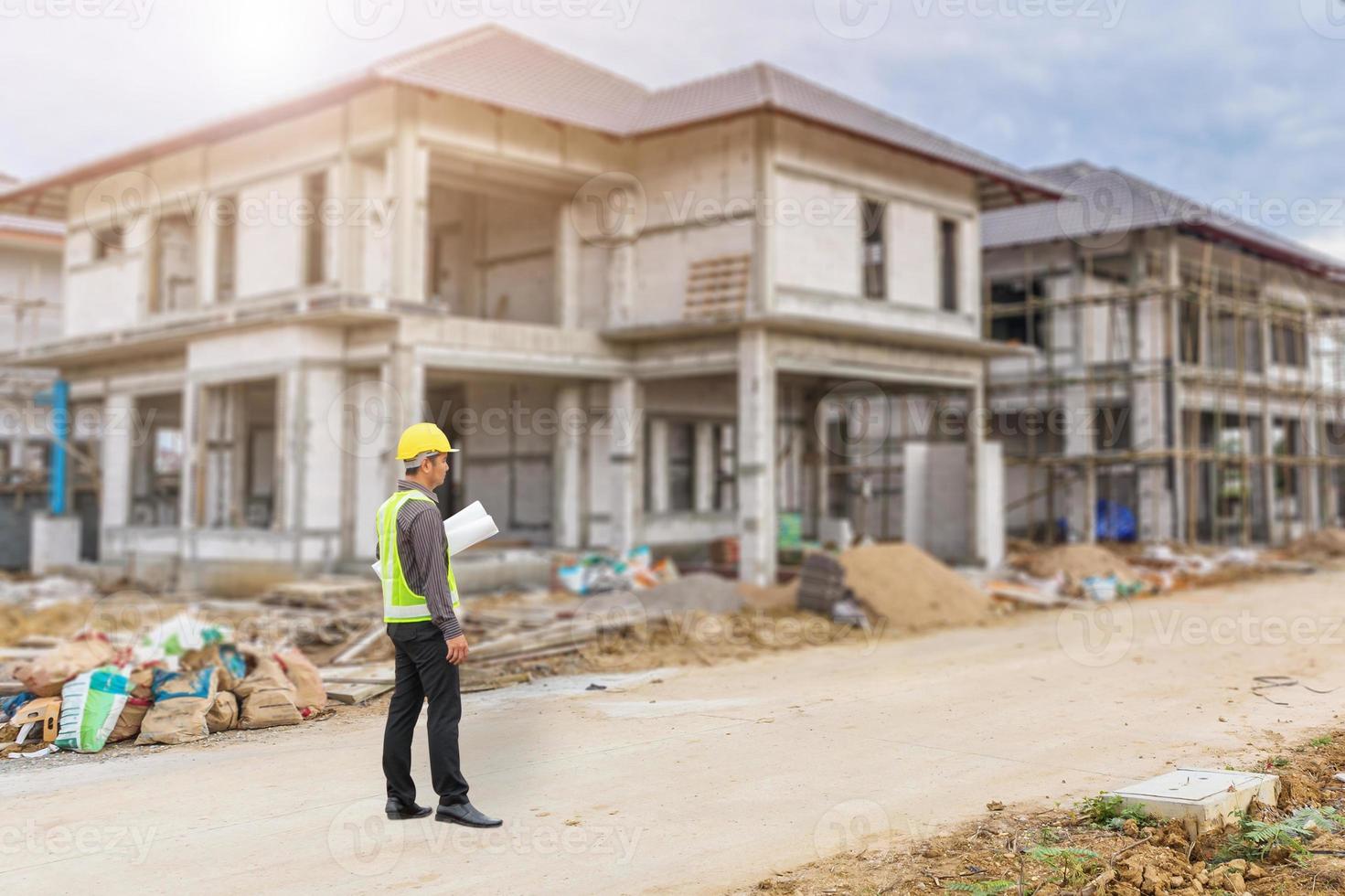 junger professioneller ingenieur in schutzhelm und blaupausenpapier auf der baustelle des hausbaus foto