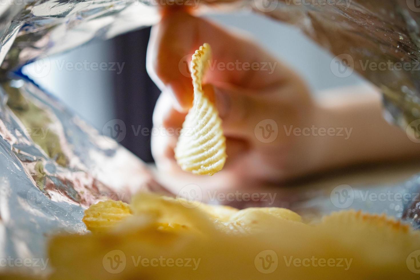 handpflückende kartoffelchips in der snacktüte foto