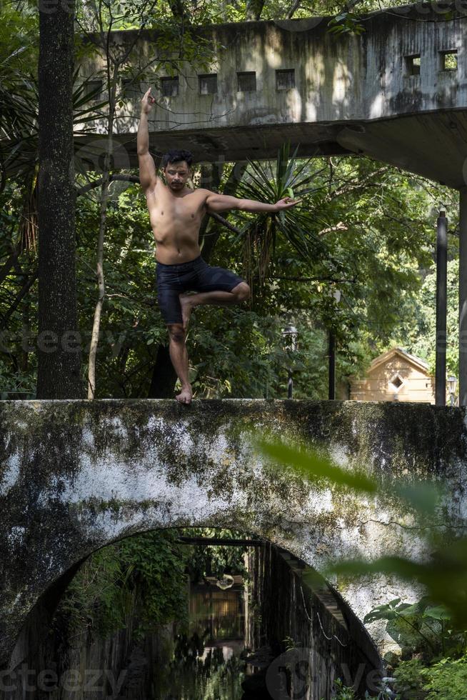 hispanischer und lateinamerikanischer mann, der mitten in einem wald meditiert, sonnenstrahlen empfängt, braune haut, mexiko foto