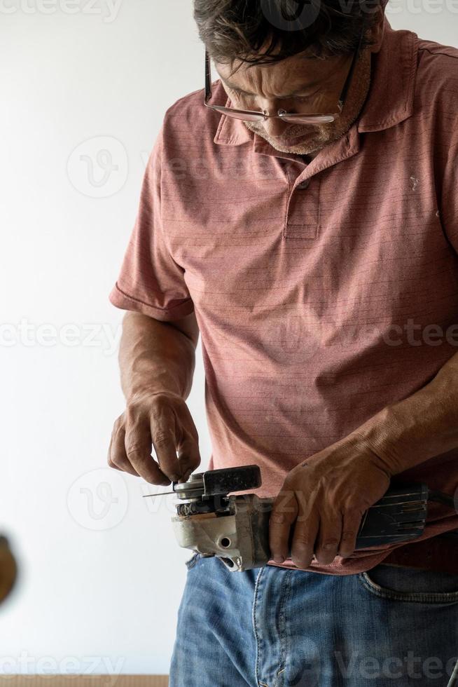 Mann mit Winkelschleifer, Schneiden einer Schraube, Reibungsfunken, Spannschraube mit Pinzette Konzentrationsgesicht und Anliegen Latino-Mann foto