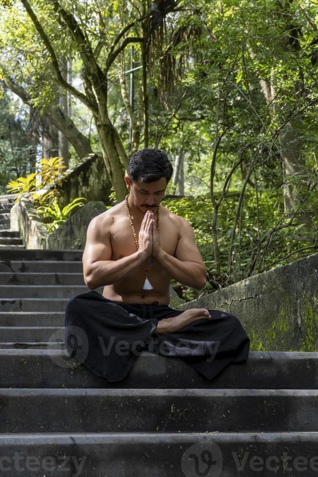 Junger Mann, der auf einer Treppe in einem Wald, Mexiko, meditiert foto