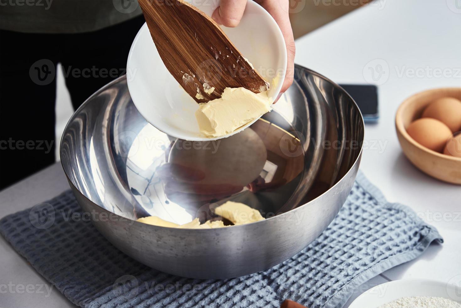 Hände geben Butter in eine Schüssel. Kochrezept foto