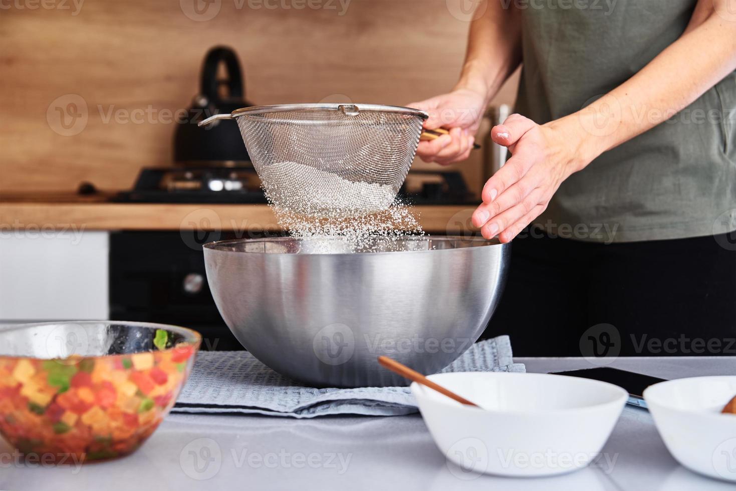 Frau in der Küche, die einen Teig kocht. Hände gießen Mehl in eine Schüssel foto