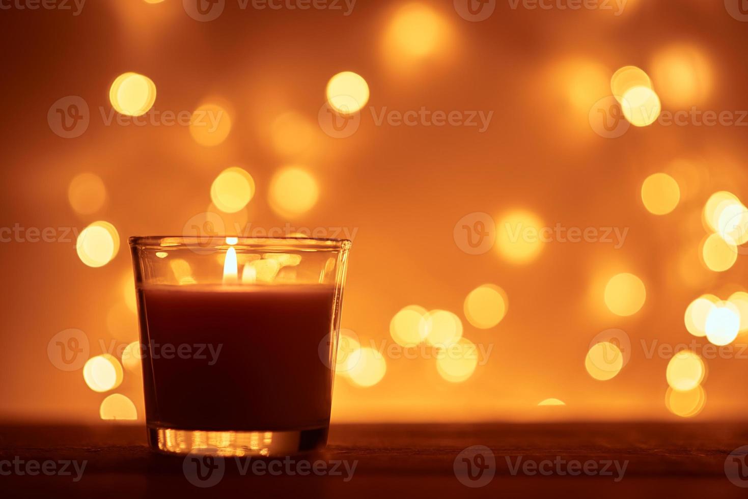 Silhouette einer brennenden Kerze mit goldenen verschwommenen Lichtern auf dunklem Hintergrund foto