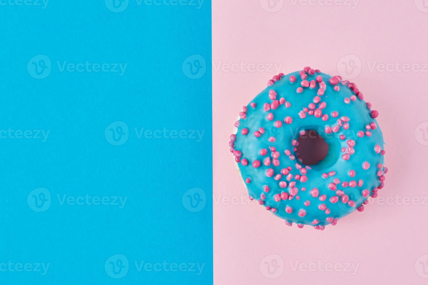 Krapfen auf einem pastellrosa und blauen Hintergrund. Minimalismus kreative Essenskomposition. flacher Lay-Stil foto