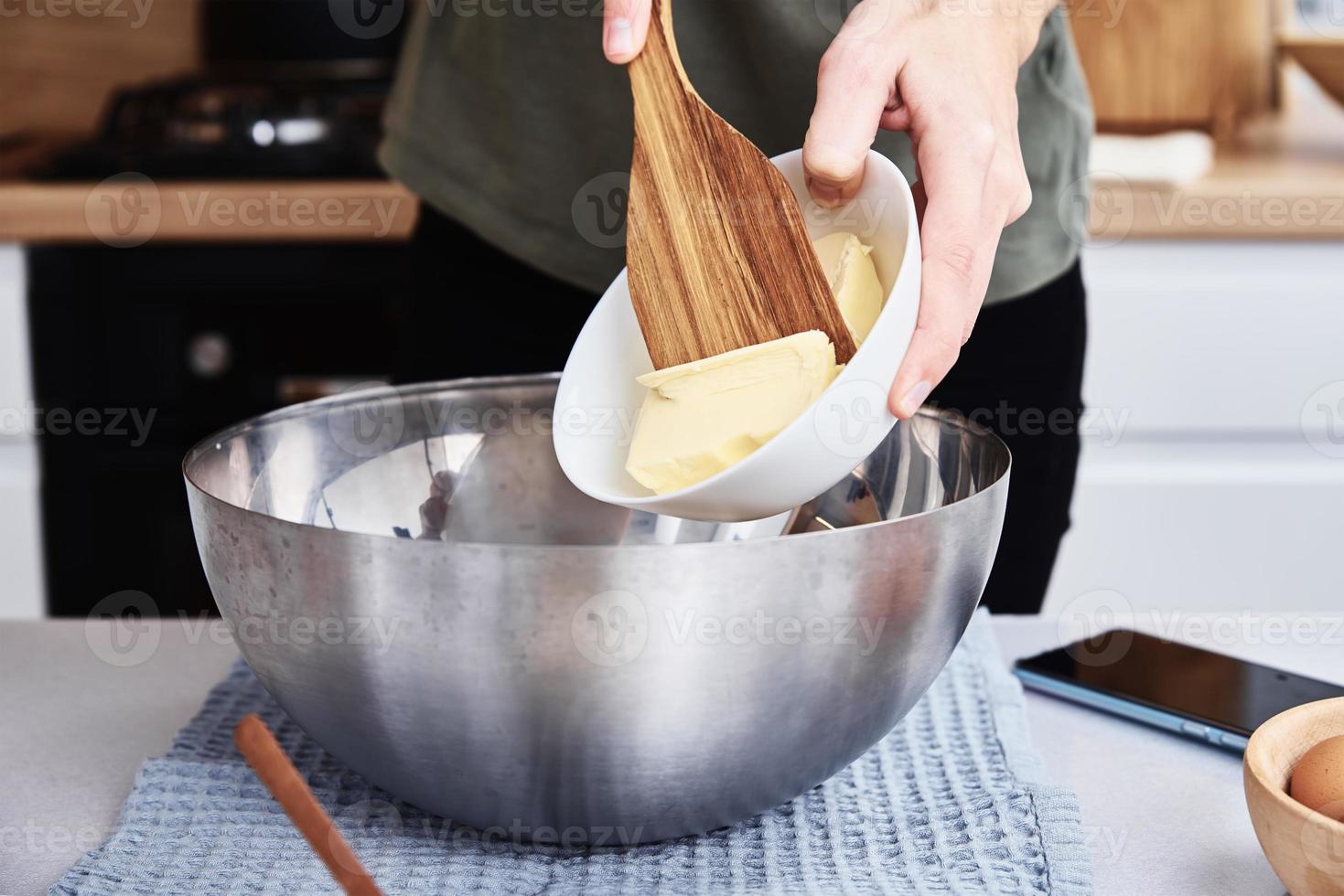Hände geben Butter in eine Schüssel. Kochrezept foto