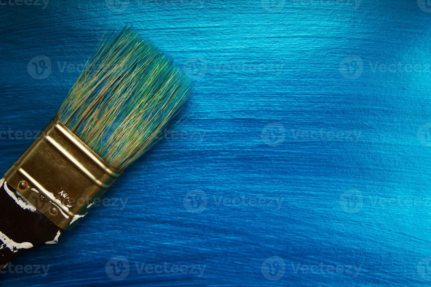 ein Pinsel auf einem blau perlmuttfarben gemalten Hintergrund. abstrakter Hintergrund. foto