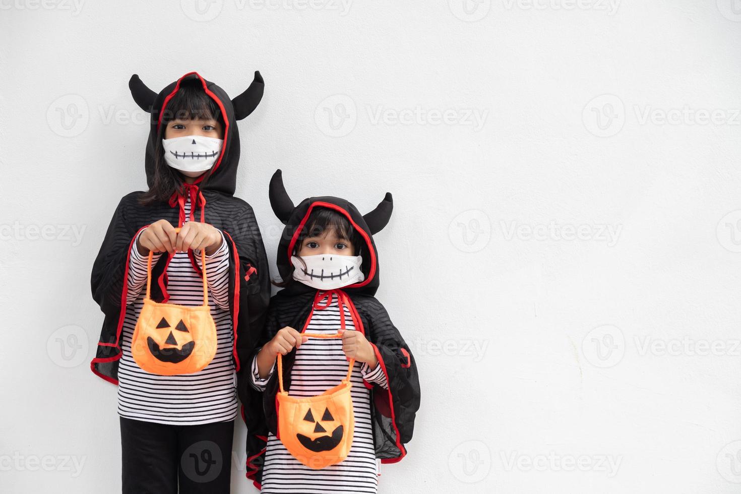 glückliche Geschwistermädchen auf der Halloween-Party. kinder, die kostüme halloweens tragen. konzept der kinder bereit für eine party. foto