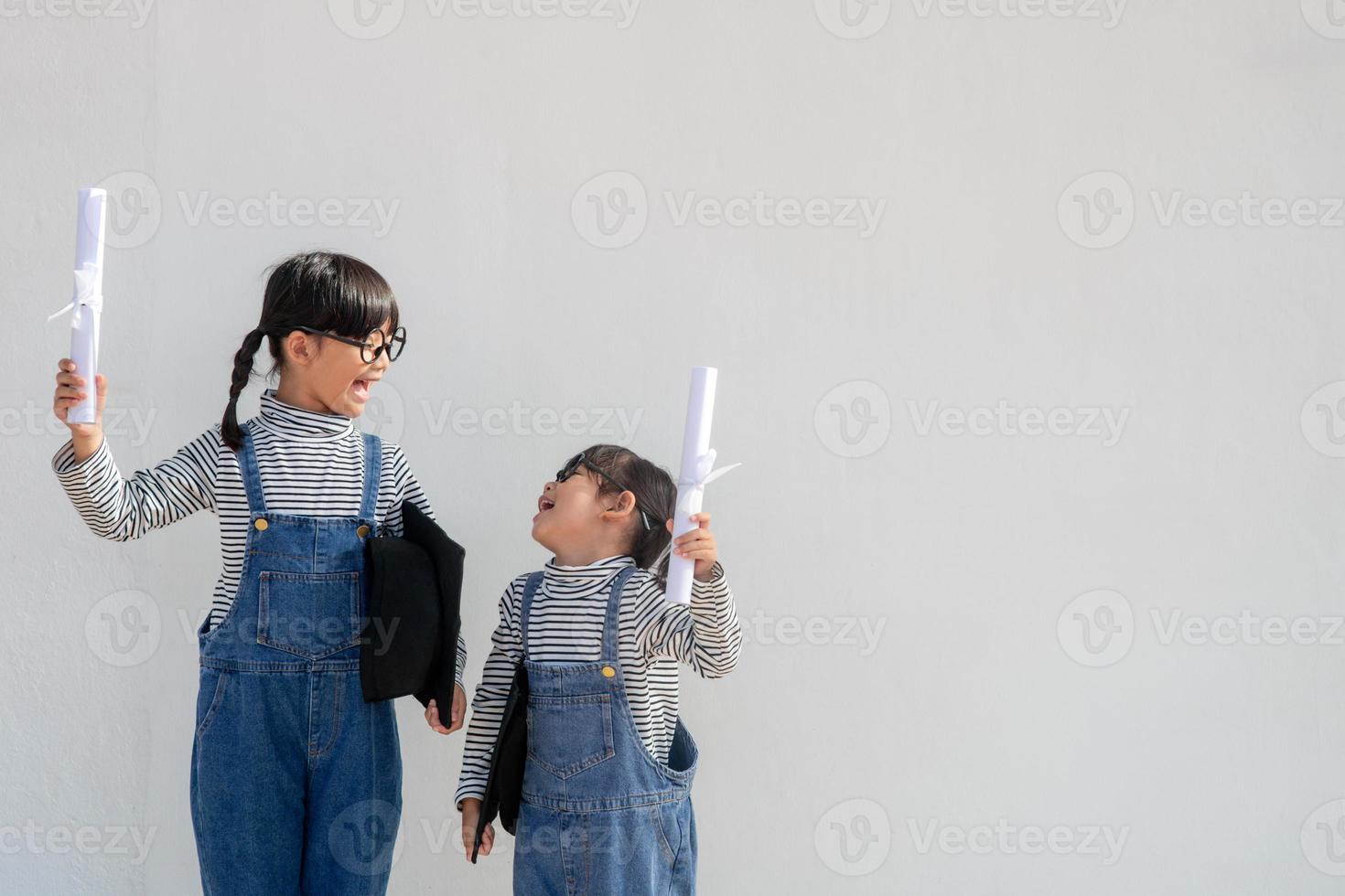 geschwister kinder mädchen abschluss mit kappe und diplom über weiß. foto