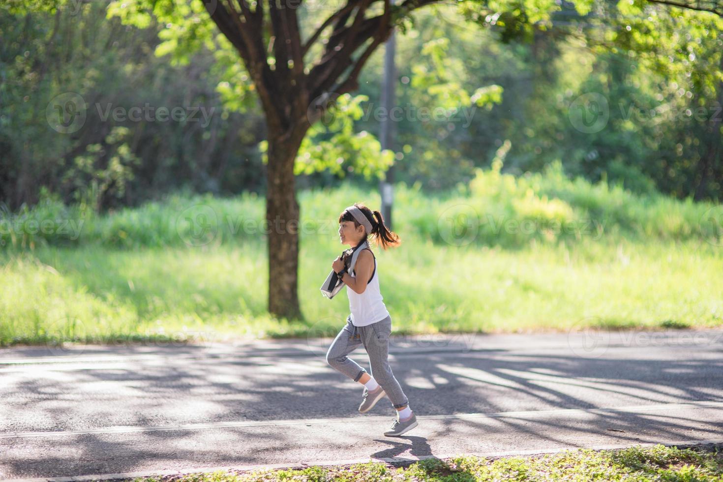 glückliches Kindermädchen, das im Sommer in der Natur im Park läuft. warmes sonnenlicht. asiatisches kleines läuft in einem park. Outdoor-Sport und Fitness, Übungs- und Wettbewerbslernen für die Entwicklung von Kindern. foto