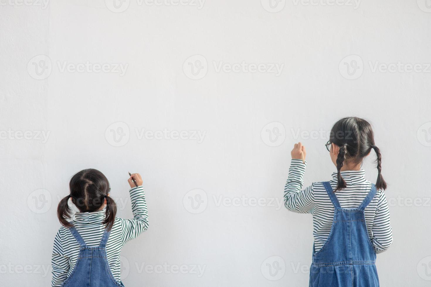 kleine kinder malen auf weißer wand foto