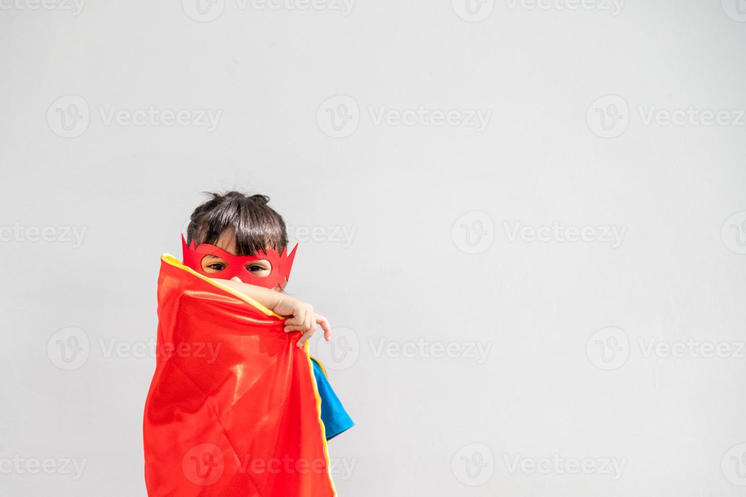 Kinderkonzept, lächelndes Mädchen, das Superheld auf weißem Hintergrund spielt foto