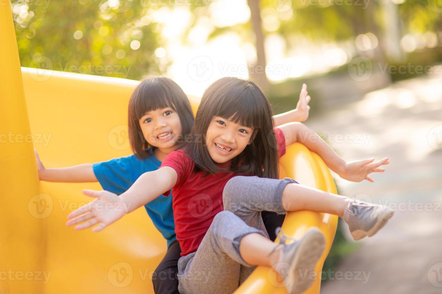 Süße kleine Mädchen Geschwister amüsieren sich an sonnigen Sommertagen auf dem Spielplatz im Freien. Kinder auf Plastikrutsche. lustige Aktivität für Kinder. aktive sportfreizeit für kinder foto