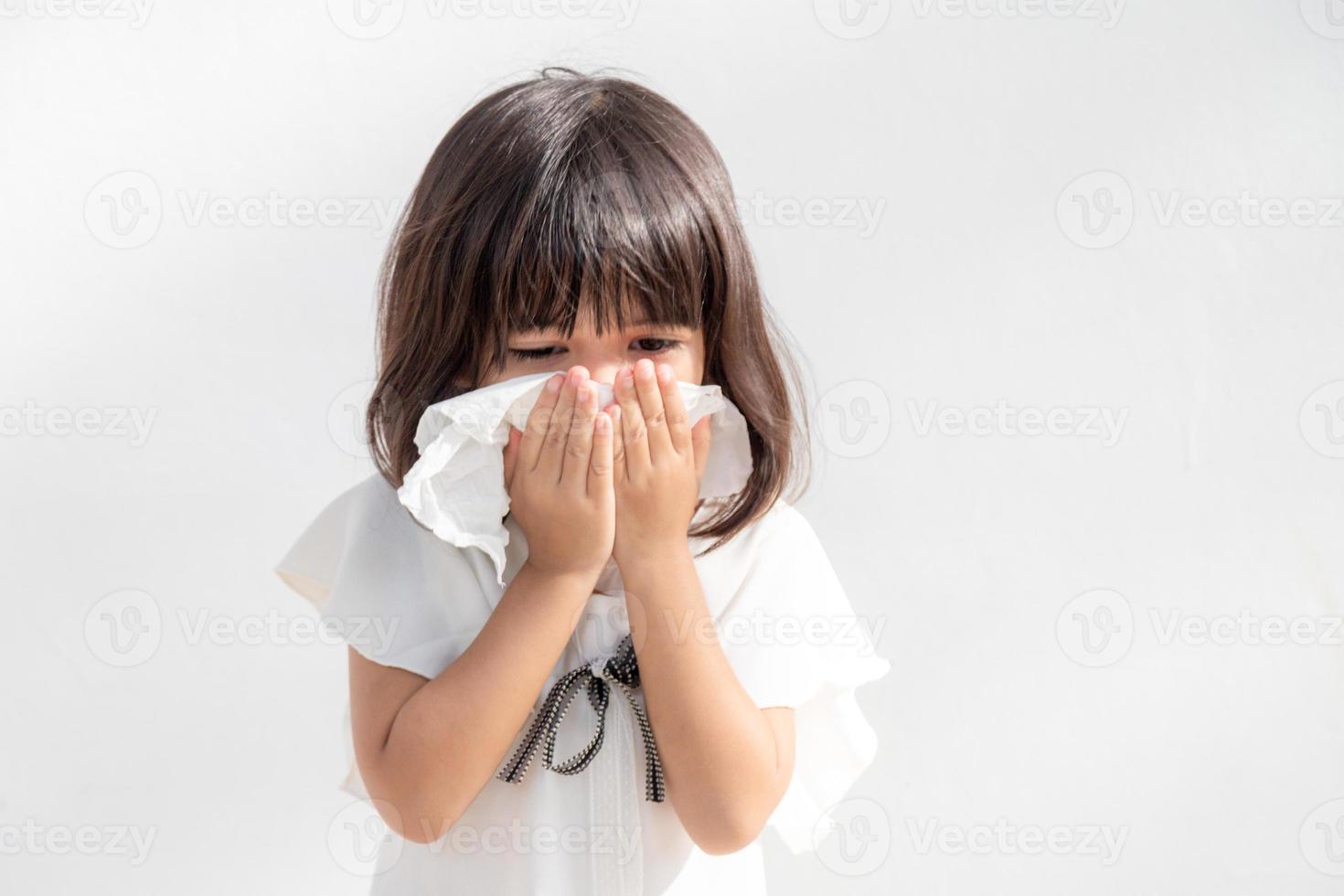 asiatisches kind mädchen krank mit niesen auf der nase und kaltem husten auf seidenpapier, weil schwach oder virus und bakterien durch staubwetter und kindergarten und vorschule foto