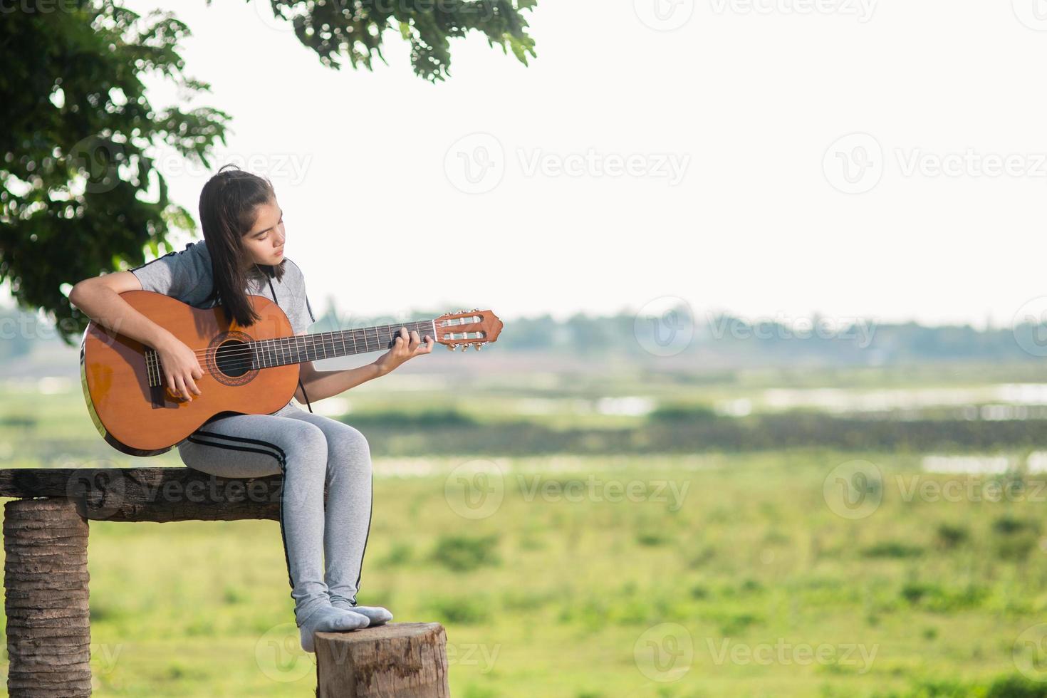 Schönes Mädchen, Gitarre spielen, singen, Musik oder Glückskonzept, warmer Lichttoneffekt bei Sonnenuntergang. foto