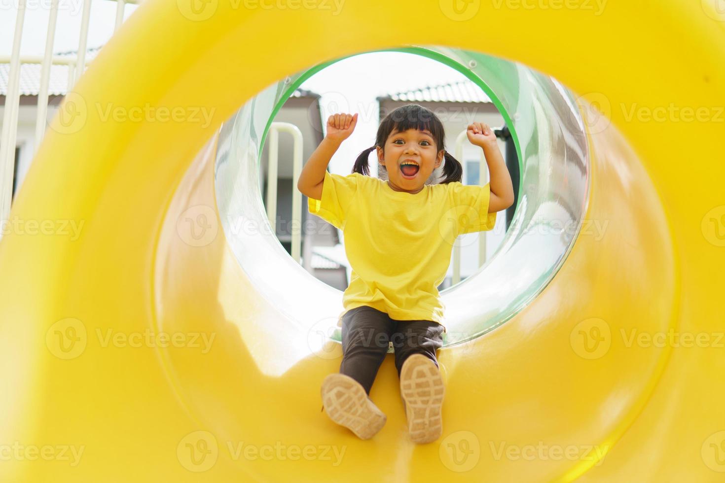 Kind spielt auf Spielplatz im Freien. kinder spielen auf dem hof der schule oder des kindergartens. aktives kind auf bunter rutsche und schaukel. gesunde sommeraktivität für kinder. foto