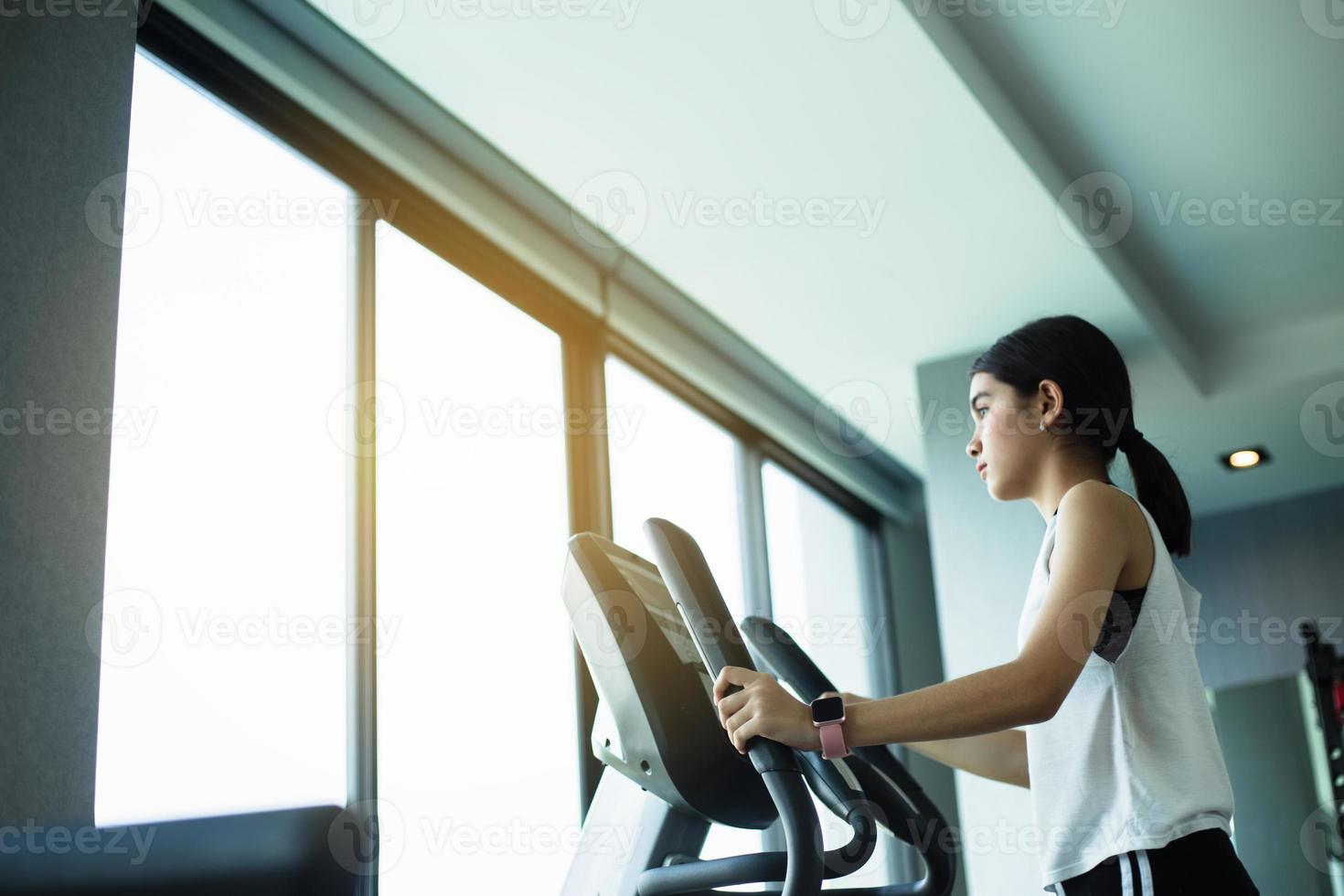 asiatische Mädchen trainieren elliptische Cardio-Lauftraining im Fitness-Studio unter Gewichtsverlust mit Aerobic-Maschine für einen schlanken und festen gesunden Lebensstil foto