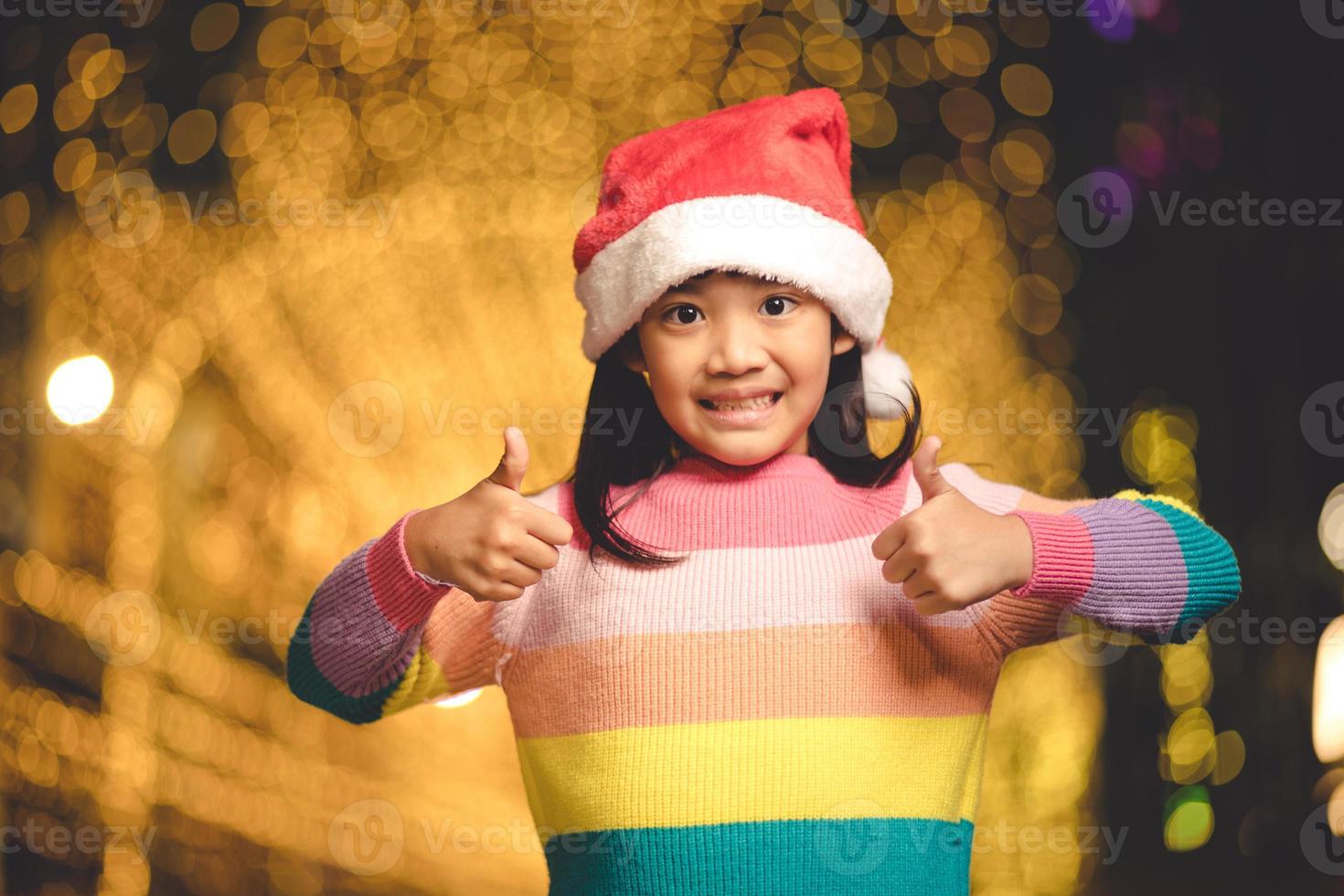 kleines Mädchen in roter Weihnachtsmütze auf Bokeh-Hintergrund. Porträt foto
