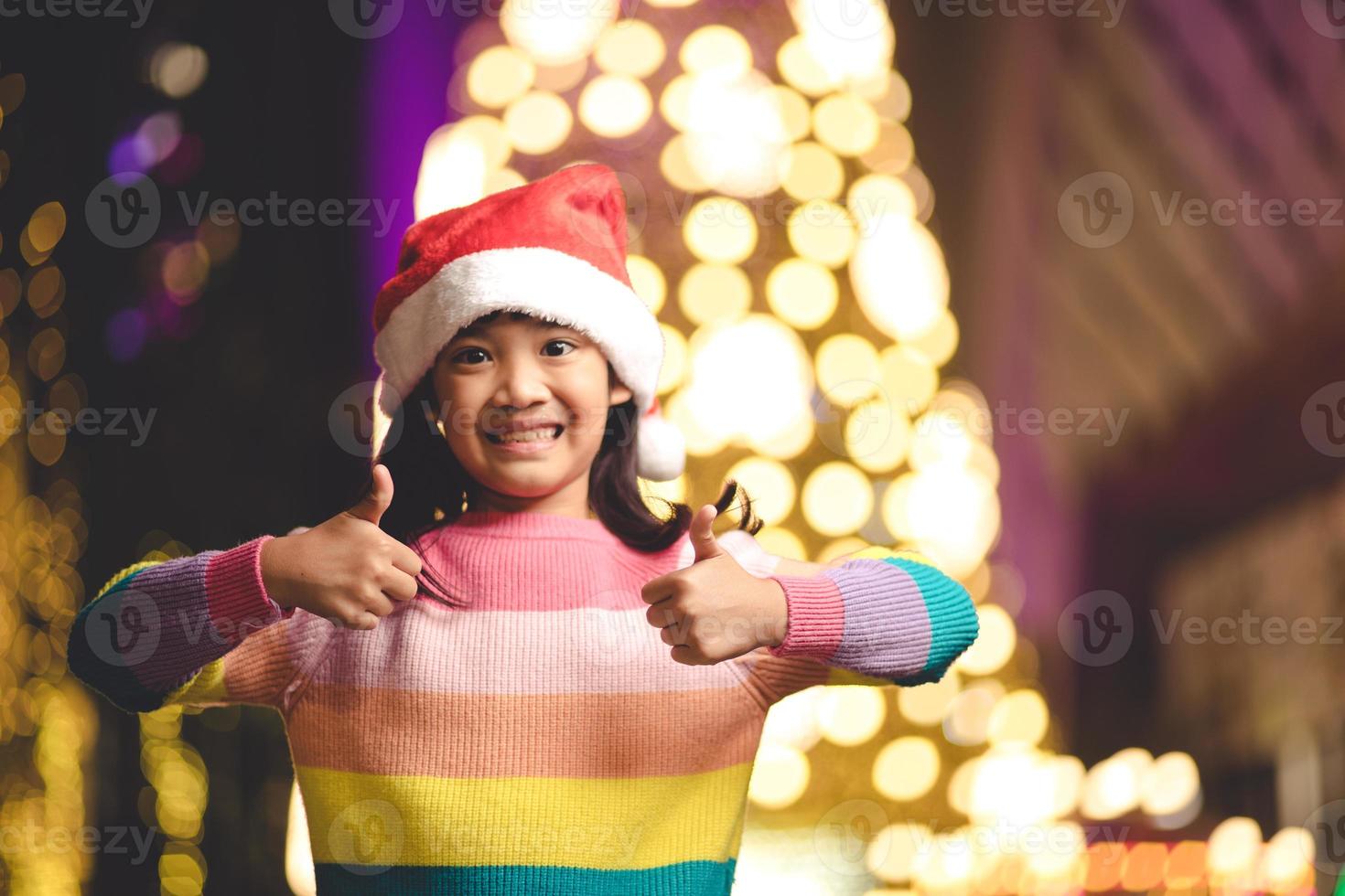 kleines Mädchen in roter Weihnachtsmütze auf Bokeh-Hintergrund. Porträt foto