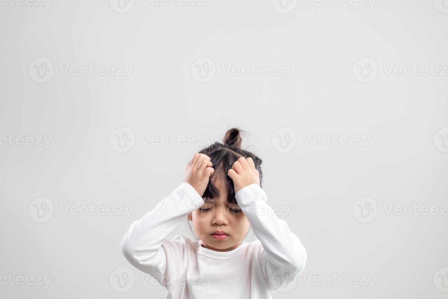 Trauriges kleines Mädchen hält seinen Kopf. kleines mädchen, das sich krank fühlt, kopfschmerzen hat. foto