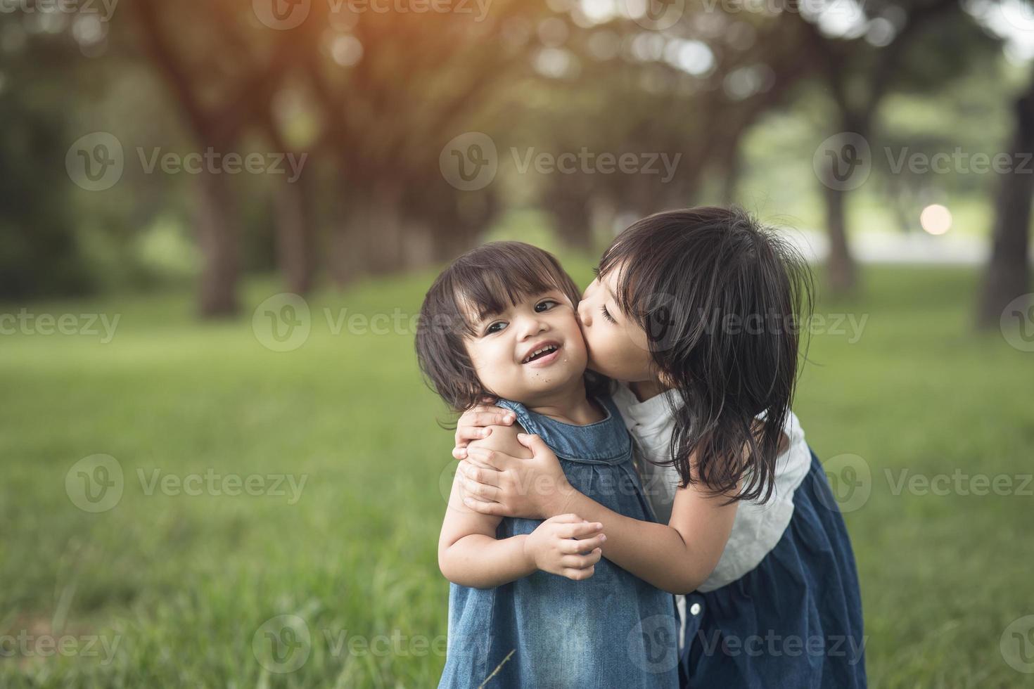 glückliche Familie. kleine Schwestern küssen und lachen im Sommer im Freien foto