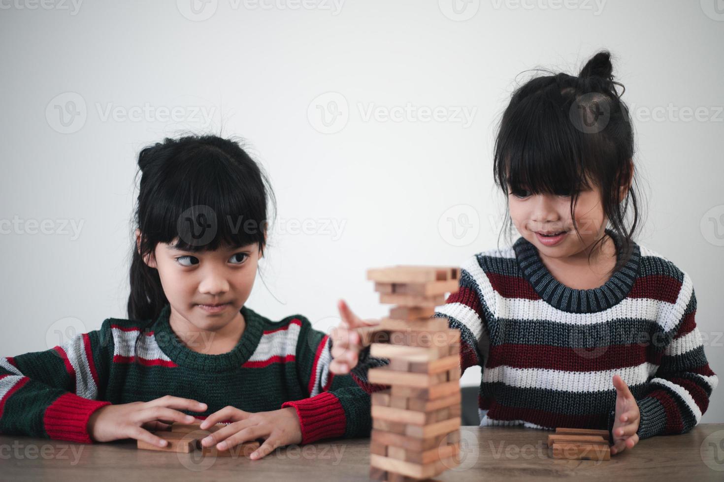 Fröhliches asiatisches Mädchen, das mit Holzbausteinen spielt. Spaß haben und Kreativität lernen. intelligentes Kinderkonzept. foto