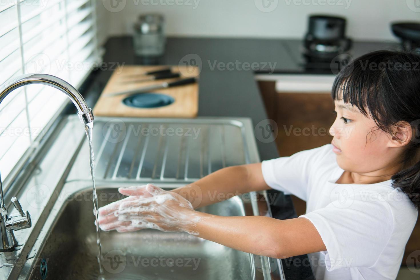 Kind wäscht sich die Hände mit Seife foto