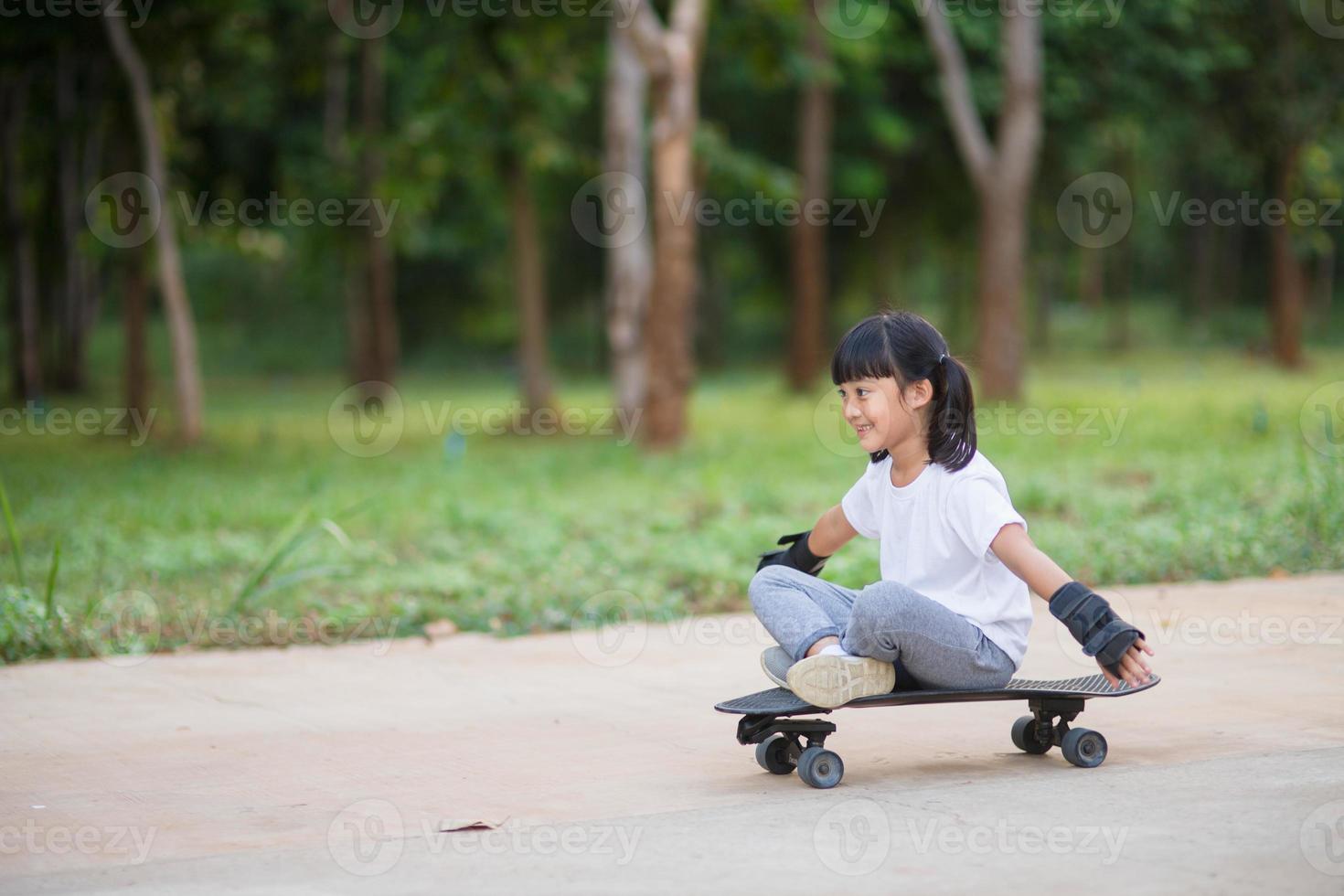 süßes kleines mädchen, das skateboard oder surfskate im skatepark spielt foto