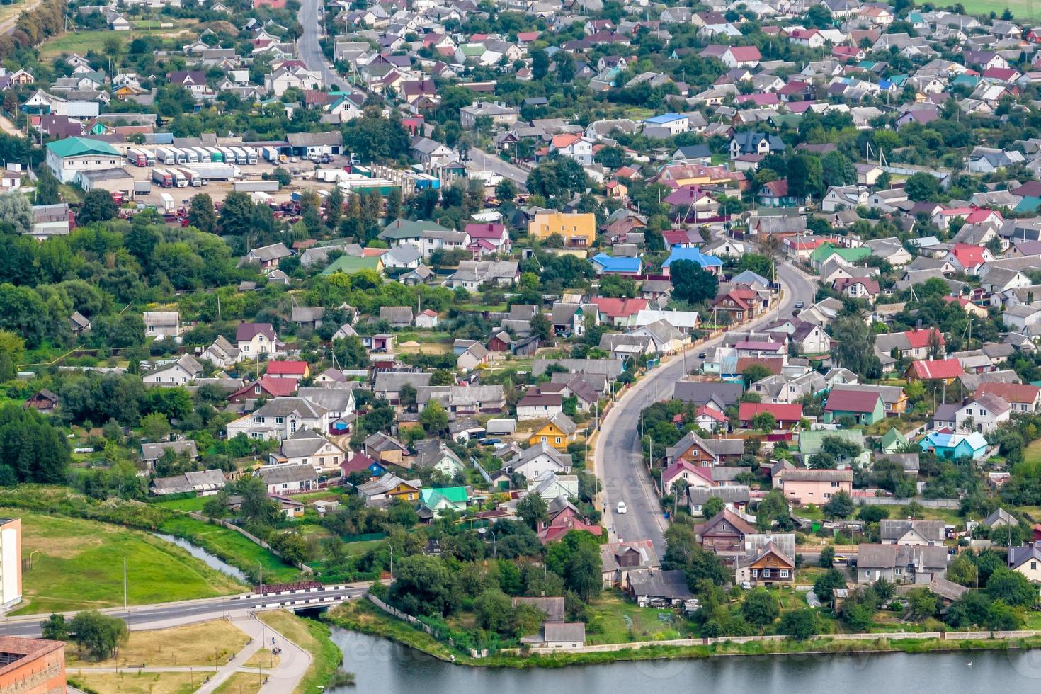 Luftpanoramablick auf das grüne Dorf mit Häusern, Scheunen und Schotterstraße im Wald foto