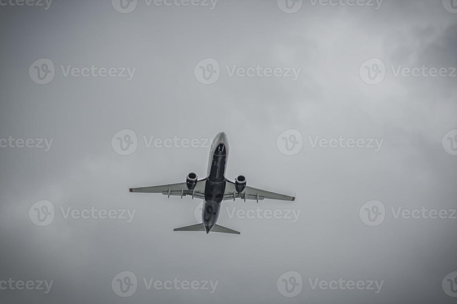 Düsenflugzeug, das vor dem Hintergrund von Regenwolken fliegt foto