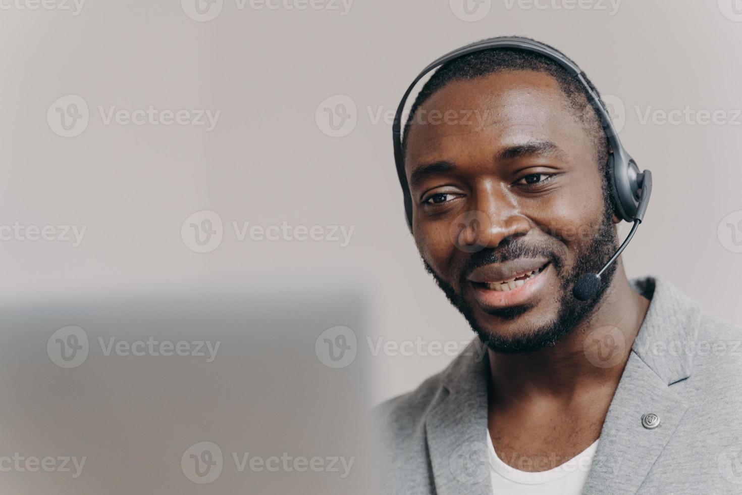 junger zufriedener afrikanisch-amerikanischer mann callcenter-agent, der mit kunden spricht und kunden online berät foto