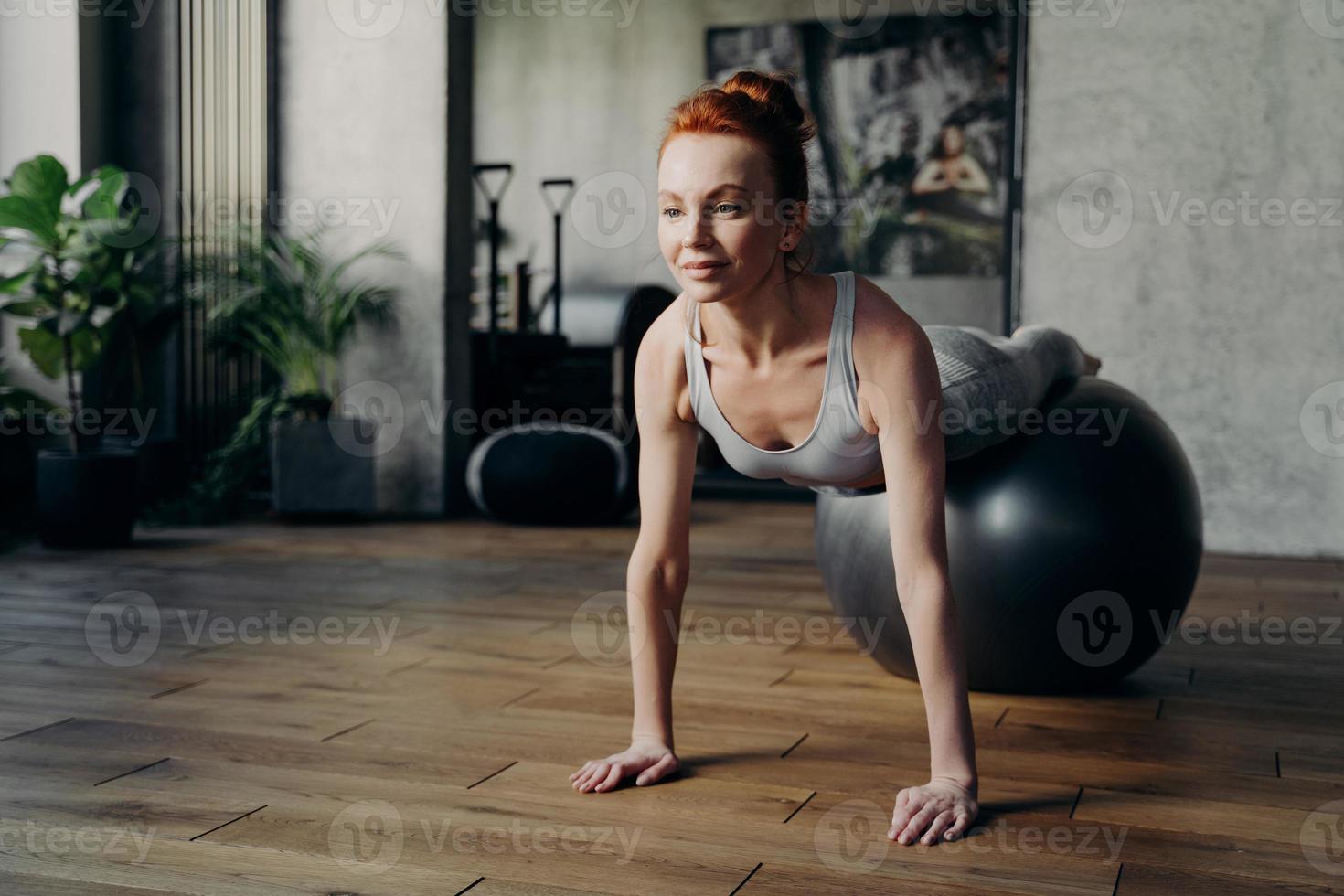 fitte Frau, die während des Pilates-Trainings auf dem Gymnastikball im Fitnessstudio balanciert foto