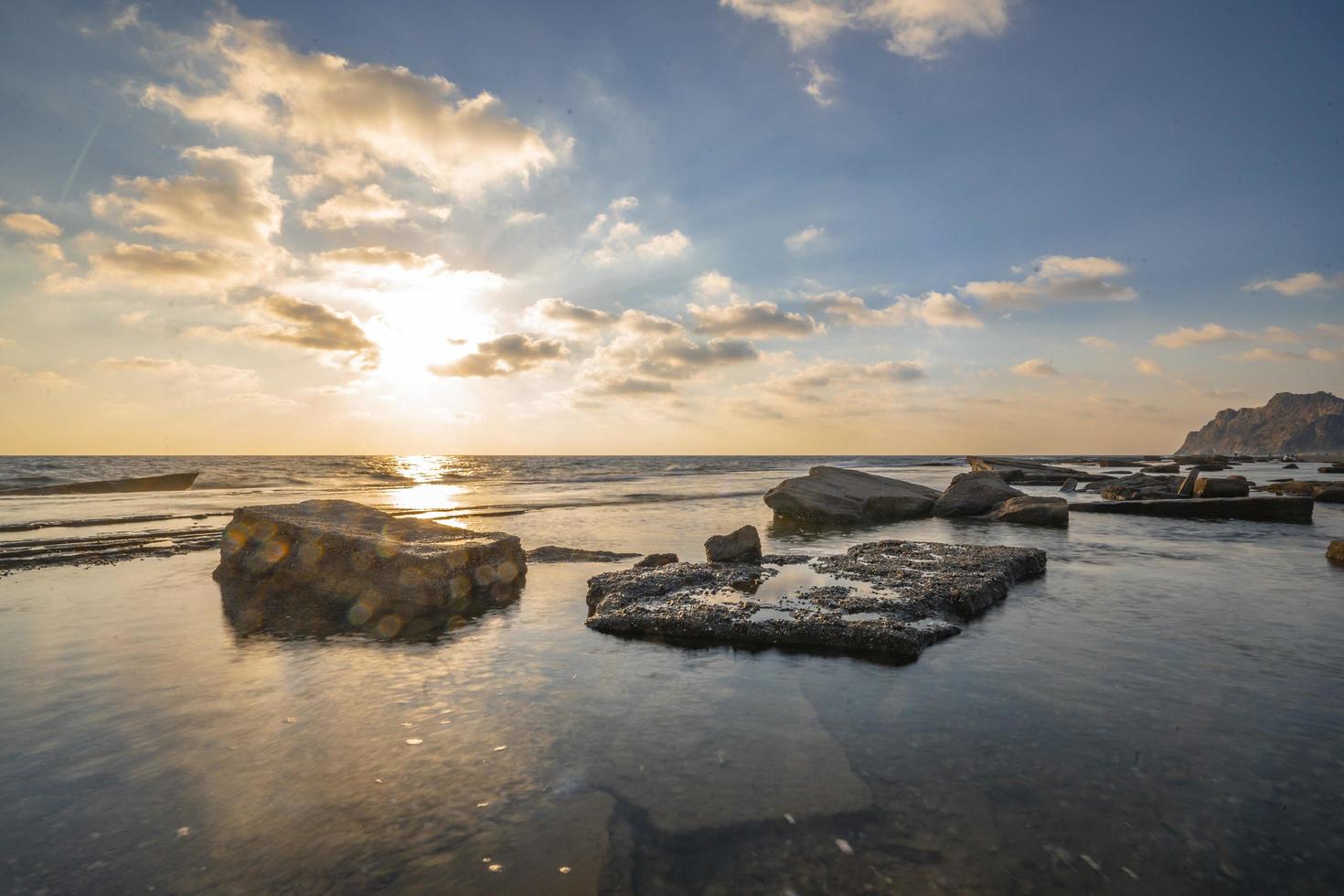 Schöne Aussicht auf das Meer mit der Sonne, die in einem blauen Himmel im Hintergrund scheint foto