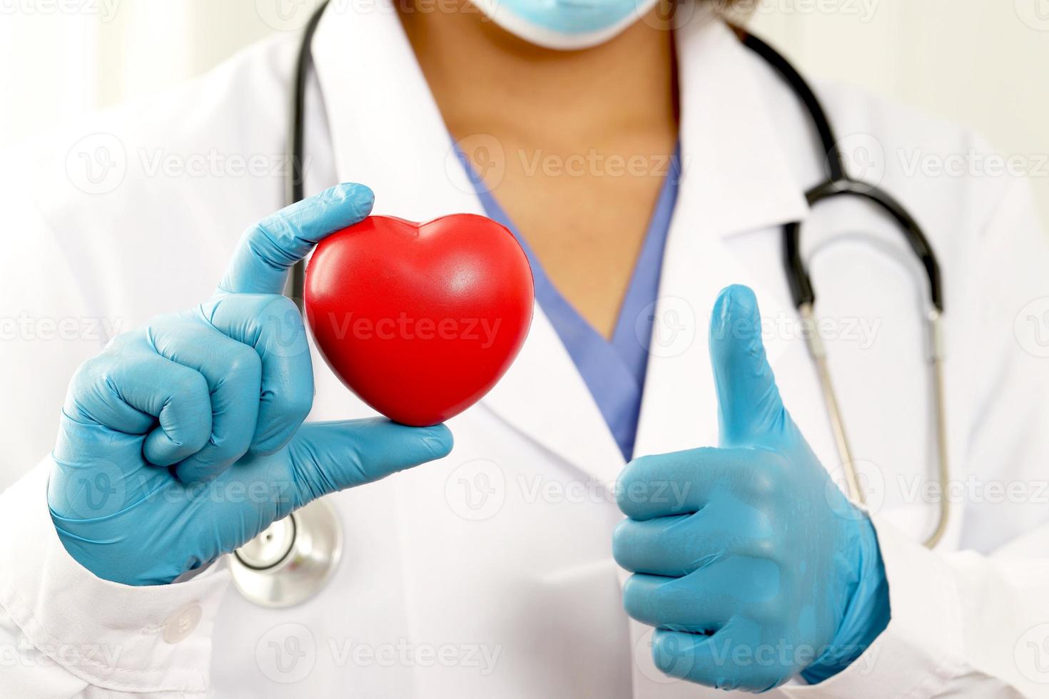 junge Ärztin, die ein rotes Herz hält, das auf einem weißen Hintergrund steht foto