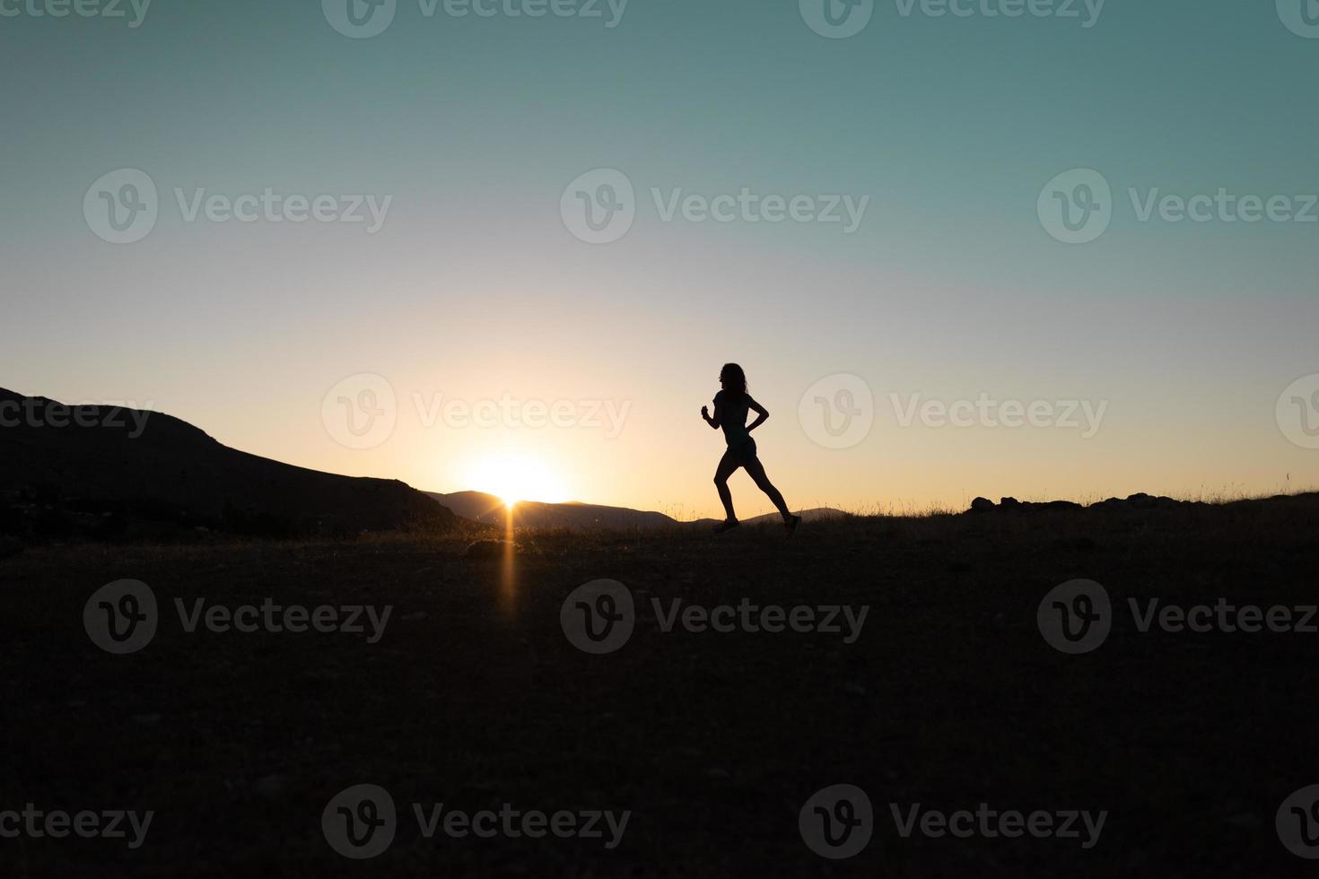 Mädchen läuft bei Sonnenuntergang in den Bergen. foto
