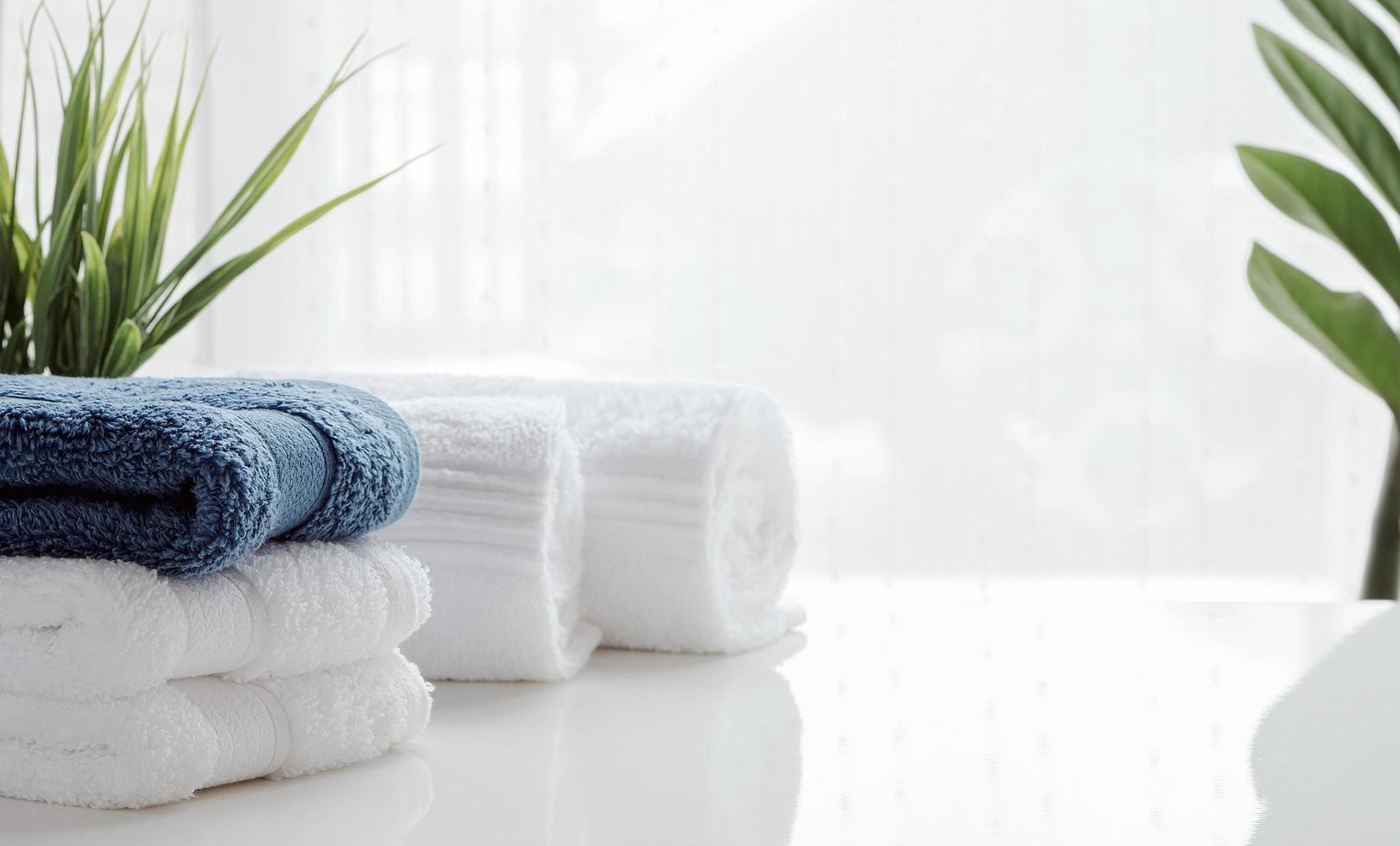 saubere Handtücher und Zimmerpflanzen auf einem weißen Tisch foto