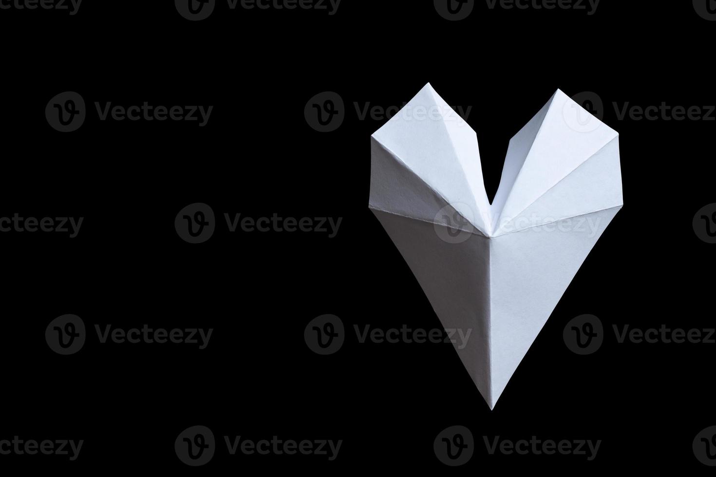 weißes Papier gefaltetes Origami-Liebesherz lokalisiert auf schwarzem Hintergrund. foto