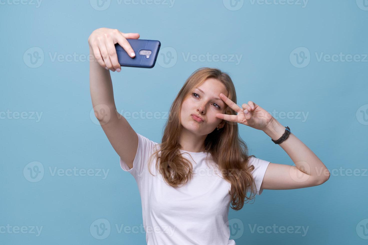 Porträt glücklich freundliches junges kaukasisches Mädchen im weißen T-Shirt auf Blau foto