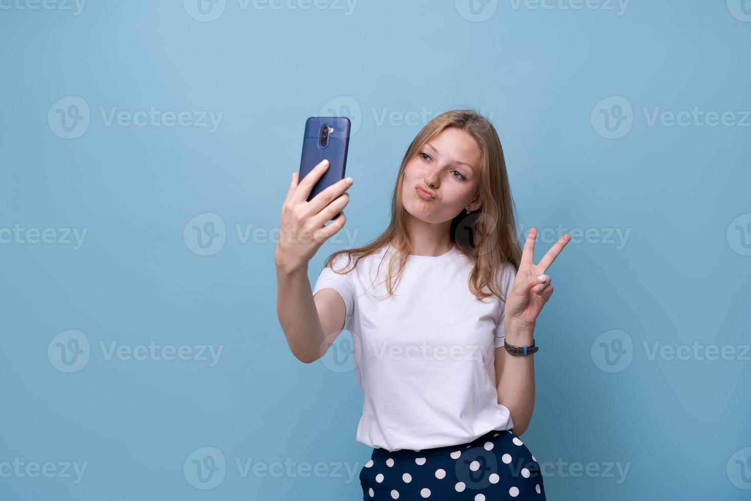 Porträt glücklich freundliches junges kaukasisches Mädchen im weißen T-Shirt auf Blau foto