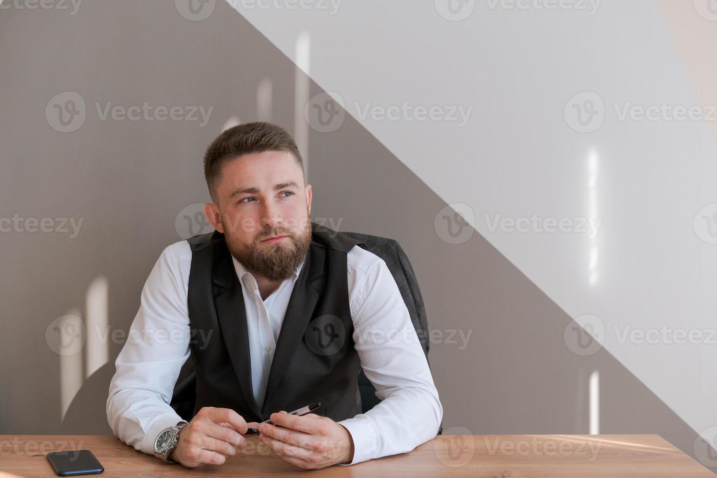 Portrait bärtiger Geschäftsmann sitzt im Büro und meditiert mit Stift in seinem foto