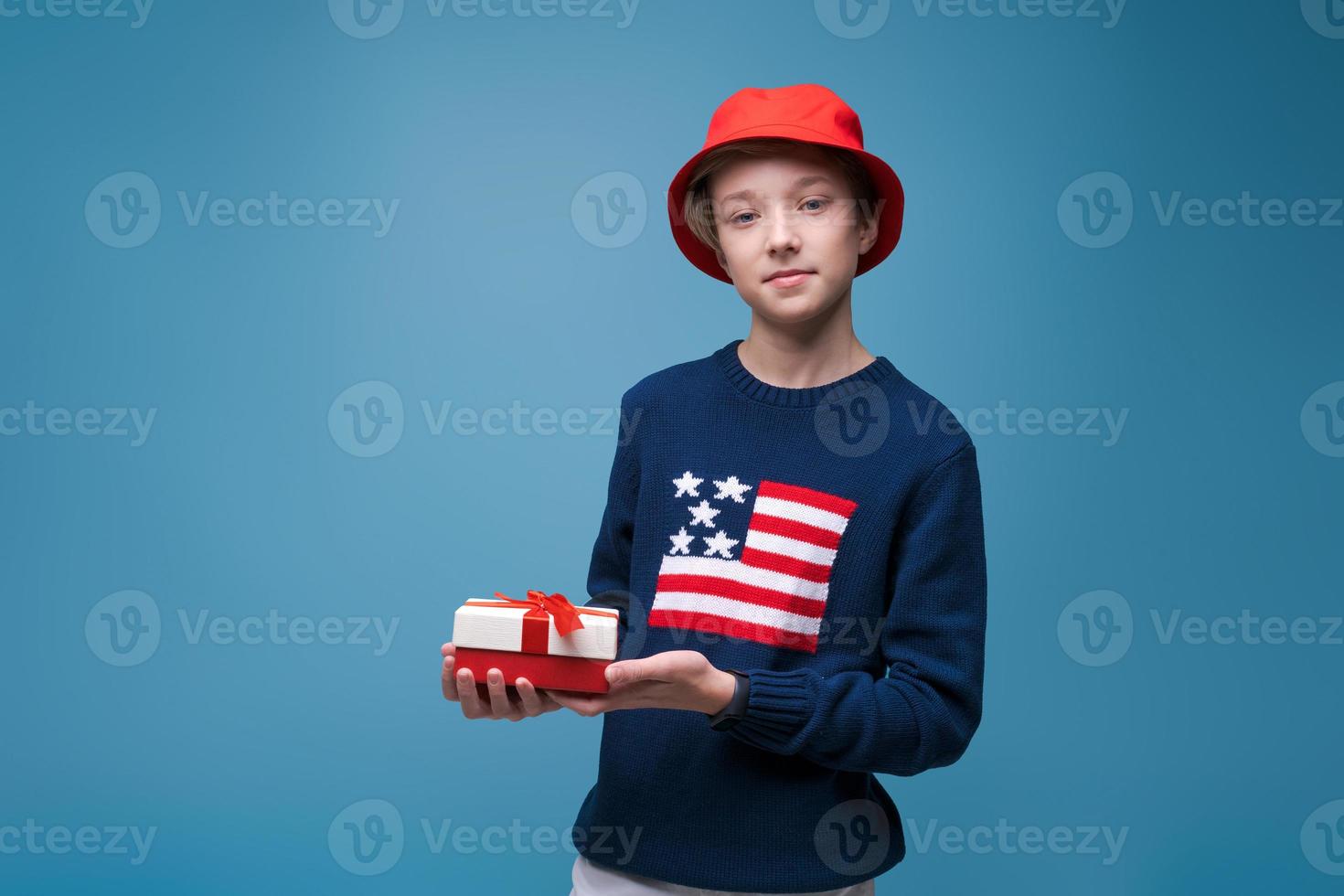 nimm dein Geschenk. Porträt eines Hipster-Typen im blauen Pullover mit USA-Flagge und foto