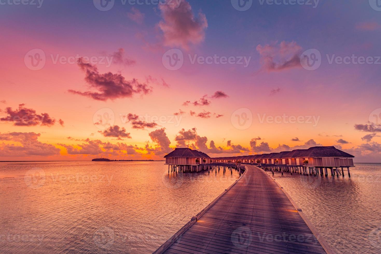 sonnenuntergang auf der malediveninsel, luxuriöses wasservillenresort und hölzerner pierweg. schöne himmelwolken und strandküste für sommerferienurlaub und reisekonzept. tropische Meereslandschaft, entspannende Lagune foto