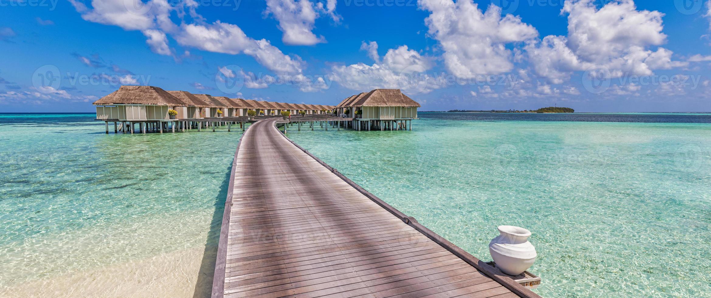 sonnige malediveninsel, luxuriöses wasservillenresort und holzsteg. schöner himmel und wolken und strandhintergrund für sommerferienurlaub und reisekonzept. erstaunlicher Panoramablick auf den Strand, Tourismus foto